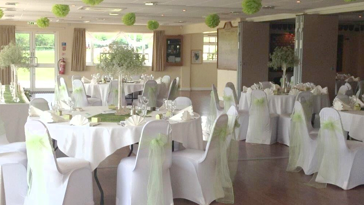 Fundas elásticas blancas para sillas de banquete con fajines de organza verde